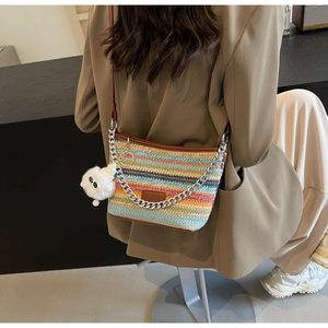 Detail of colorful striped woven bucket bag with leather trim and silver chain strap