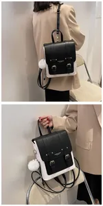 Detail of contrast PU leather backpack featuring metal buckles and a plush pompom charm