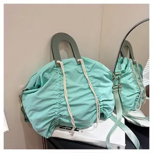 Detail of mint green pleated canvas handbag with leather handle and cream drawstring accents
