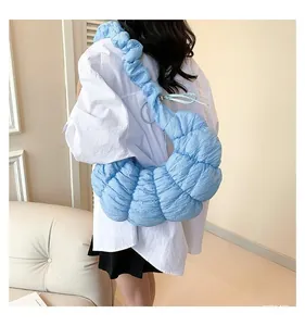 Détail du sac croissant bleu ciel avec texture plissée 3D et large bandoulière souple