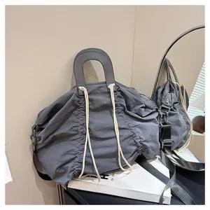 Close-up of grey drawstring pleated canvas tote bag on a white book in minimalist setting