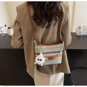 Detail of colorful striped straw bucket bag with plush charm and silver chain strap
