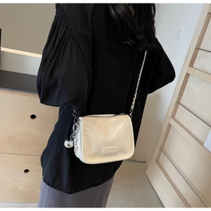 Détail du sac en cuir blanc crème avec chaîne argentée et breloque boule métal