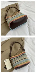 Close-up of the bohemian woven straw bag showing colorful stripes and brown leather base