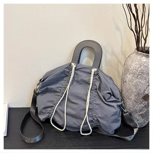 Detail of grey pleated nylon tote bag with white drawstring and hard circular handles