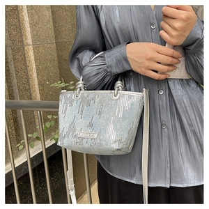 Detail of light blue denim handbag with silver sequins and metallic round handle