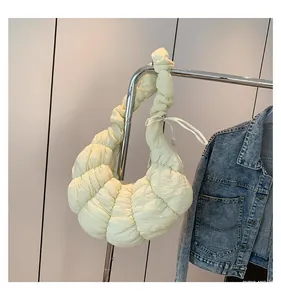 Détail du sac croissant jaune pâle avec texture plissée et détail de nœud élégant
