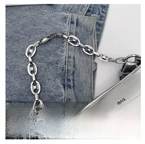Détail du sac argenté avec poignée en chaîne d'ancre métallique sur fond de denim