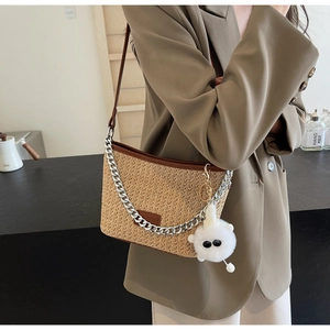 Detail of woven straw tote bag with silver chain and plush charm on female model