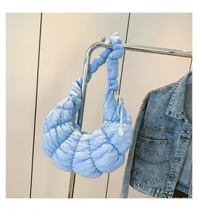 Détail du sac croissant bleu avec texture plissée douce sur un cintre métallique