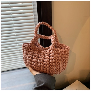 Dettaglio di borsa a secchiello intrecciata a mano rosa antico con trama a maglia incrociata