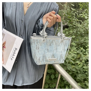 Detail of light blue sequined handbag with silver twisted handles and textured finish