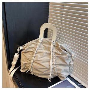 Detail view of the pleated light beige crossbody bag with circular handle and fabric strap