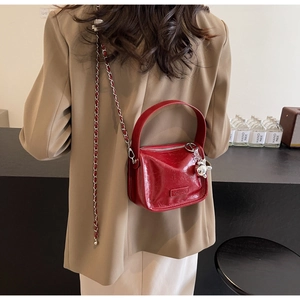 Détail du sac rouge brillant avec breloque lapin argentée et bandoulière sur le mannequin