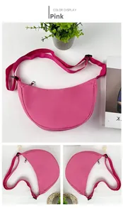 Sac croissant en nylon rose avec bandoulière réglable et fermeture éclair sur bureau blanc