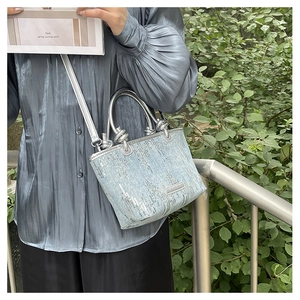 Detailed close-up of light blue sequined handbag with silver knot metal handle