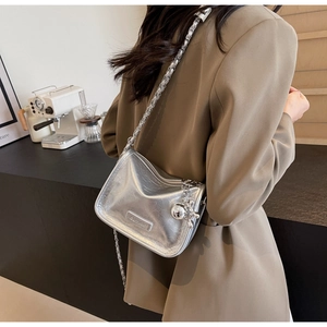 Détail du sac bandoulière argenté métallisé avec chaîne épaisse sur un blazer kaki chic