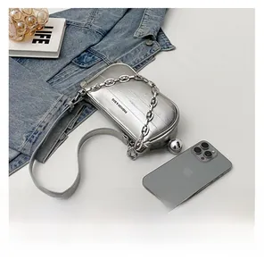 Comparaison détaillée du mini sac argenté avec un téléphone pour montrer sa taille