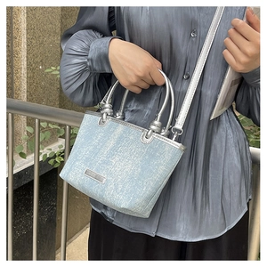 Detail of light blue denim handbag with silver ring handles and matching shoulder strap
