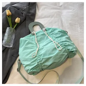Detail of mint green nylon pleated bag with drawstring closure and round top handle