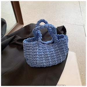 Dettaglio ravvicinato della borsa a mano blu in maglia spessa con trama intrecciata a rilievo
