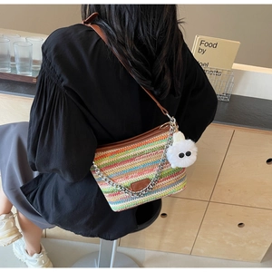 Detail of colorful woven straw bucket bag with leather strap and decorative eye charm