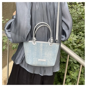 Light blue glitter denim crossbody bag with silver handles shown in a street style shot