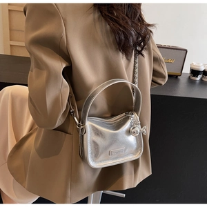 Sac à bandoulière argenté métallisé avec chaîne et charm lapin porté par un mannequin