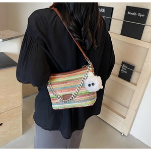 Detail of colorful striped woven bucket bag with leather strap and plush pom-pom charm