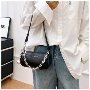 Détail du sac baguette noir avec chaîne argentée et breloque sphère sur cuir verni croco