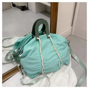 Detail of mint green nylon shoulder bag with drawstring pleats and leather handles