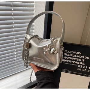 Détail du sac à bandoulière argenté métallisé avec texture froissée et breloque chien