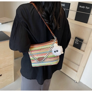 Close-up of colorful striped woven straw bucket bag with leather strap and chain detail