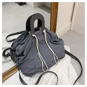 Detail of grey pleated nylon bag with round handles and white cord decorative accents