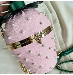 Close-up of strawberry bag featuring pink pebbled leather and gold metal clasp hardware