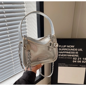 Détail d'un sac argenté métallisé avec texture plissée, chaîne et breloque chien ballon