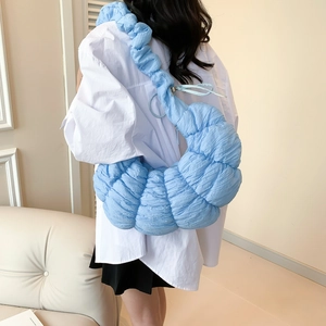 Sac croissant bleu clair avec design plissé et large bandoulière dans un cadre décontracté