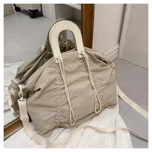 Detailed close-up of beige pleated canvas tote bag with cream leather handles and strap