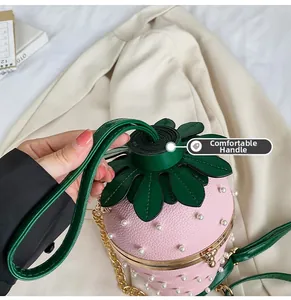 Detail of pink strawberry bucket bag with pearl accents and green leaf lid decoration