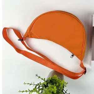 Détail d'un sac bandoulière croissant en nylon orange avec sangle réglable sur fond lifestyle