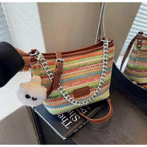 Detail of colorful woven straw bucket bag with leather strap and silver chain accent