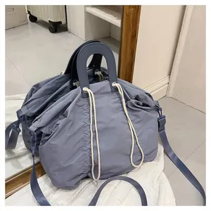 Detail of blue pleated tote bag showing the drawstring closure and sturdy handles