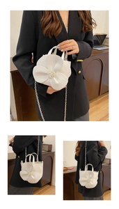 Detailed close-up of white 3D camellia flower bucket bag with pearl center and chain