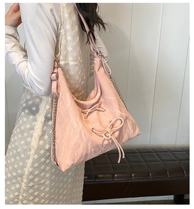 Detailed view of pink pleated leather hobo bag with drawstring bow and chain strap