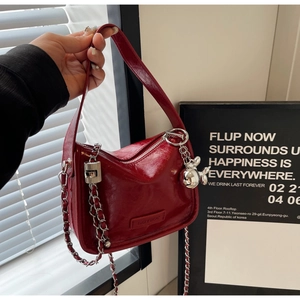 Détail du sac à bandoulière en cuir verni rouge avec chaîne argentée et lapin