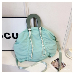 Detail of mint green pleated canvas handbag with drawstring closure and green top handle