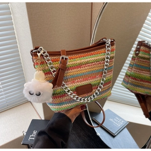 Detail of colorful woven straw bucket bag with metal chain and leather trim