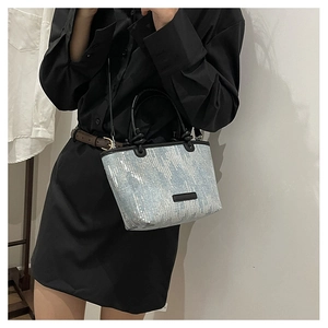 Close-up of light blue sequined handbag with black leather handles and shoulder strap