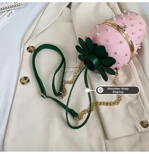 Detail showing pink strawberry bucket bag with pearl accents and a chain strap