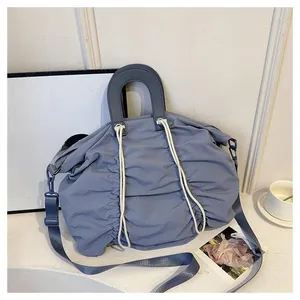 Detail of blue pleated nylon handbag with white drawstrings and leather handles